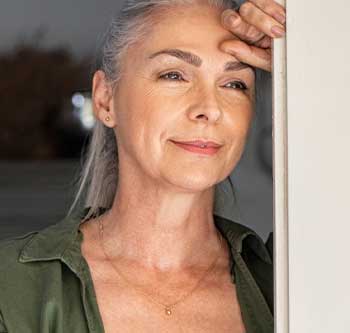 Older woman leaning against a door frame