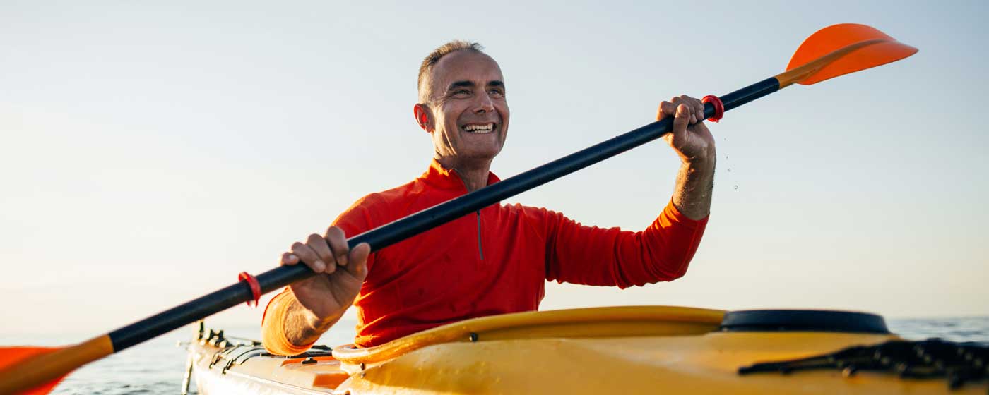 A retired man in a yellow kayak paddling on the water